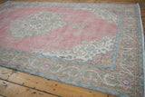 Distressed pink field of a vintage Sparta carpet, showing wear to knot heads and pale floral patterns.