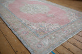 Distressed vintage Sparta carpet featuring a soft pink field and faded pastel border.