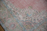 Distressed vintage Sparta carpet border with worn pink, blue, green arabesque pattern, knot heads.