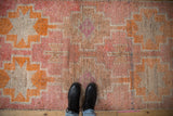 Distressed Kurd runner pile with stepped medallions in coral, blush, and ivory.