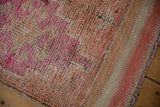Distressed Kurd rug pile, faded coral, beige, and blush, with visible foundation and flatwoven edge.