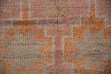 Distressed Kurd rug pile in faded coral, blush, beige geometric. Faint foundation visible.