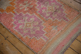 Distressed texture and geometric patterns in faded coral, pink, ivory on vintage Kurd rug edge.
