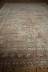 Fringed distressed Oushak rug border with pale raspberry and oxidized silver geometric patterns.