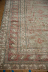 Distressed vintage Oushak rug corner, showing stepped medallion and faded raspberry patterns.