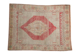 Faded raspberry red pinwheel medallion on an abrashed ivory Oushak rug.