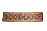 Distressed Kurd runner rug featuring geometric navy blue diamonds on faded orange and beige field.