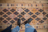 Distressed vintage Kurd runner with geometric navy diamond panels and varied pile texture.