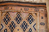 Distressed vintage Kurd rug border showing navy geometric diamonds and textured orange, beige pile.