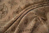 Folded textured pile of the distressed Turkmen carpet showing dusty rose and brown geometric gul motifs.