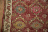 Detail of the distressed Kurd rug's dusty red selvage, ivory border, and textured floral motifs.