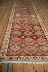 Vintage Kurd runner's distressed pile, white fringe, and ivory border with floral motifs.