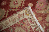 Distressed Kurd rug fold reveals hand-knotted pile, woven foundation, dusty red, ivory florals.