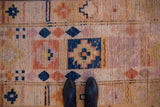 Distressed vintage Kurd runner showing wear, checkered diamond motifs, peach and navy.