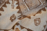 Pale coffee and ivory geometric patterns on the textured pile of a distressed Kurd runner.