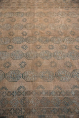 Distressed vintage Ersari carpet detail, dusty teal geometric border motifs on pale coffee brown.