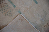 Distressed vintage Sparta rug showcasing worn ivory pile, exposed foundation, and intact side selvage.