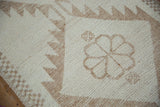 Textured short pile of distressed Kurd rug runner with cream and pale brown geometric floral motif.