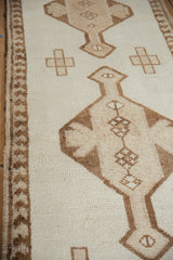 Distressed vintage Kurd runner featuring geometric finial and pawn border texture.
