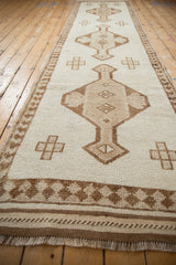 Distressed Kurd runner showing its textured ivory and coffee brown pawn border and side selvages.