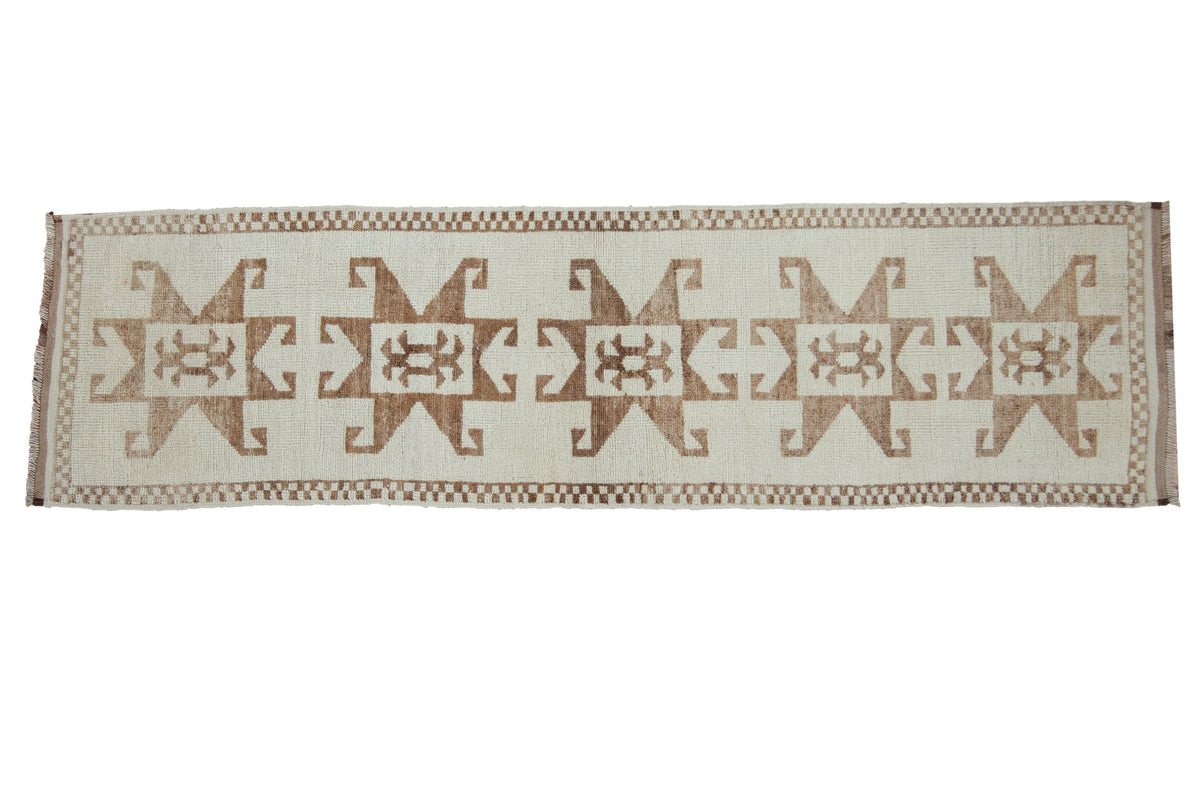 Distressed Kurd runner with a column of bold hook and latch motifs in brown on ivory.