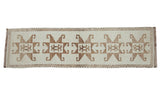 Distressed Kurd runner with a column of bold hook and latch motifs in brown on ivory.