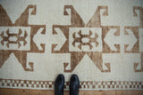 Textured short pile of a distressed Kurd rug with brown hook and latch designs.