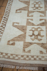 Close-up of the even, short pile on a vintage Kurd runner, highlighting the primitive brown latch-hook motifs and checkered border.