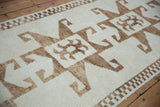 Close-up on the pale chocolate brown hook and latch motif against the ivory short pile.