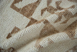 Close-up of the short, hand-knotted pile of a vintage Kurd rug in ivory and bronze.