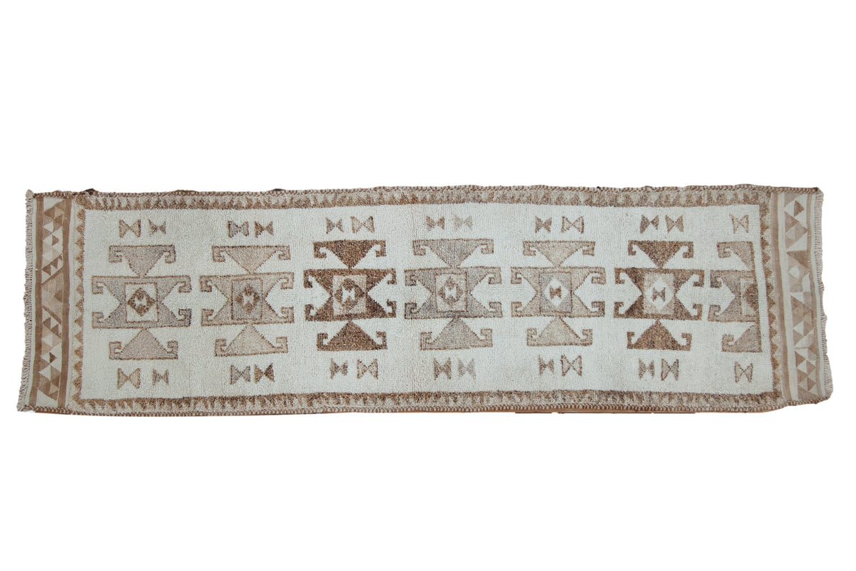 Vintage Kurd runner with geometric rams horn medallions in shades of brown over a distressed ivory field.