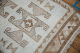 Geometric rams horn and triangle border in brown and ivory on a distressed Kurd runner.