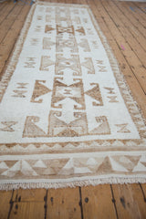 Low angle view of a distressed Kurd runner's length and repeating geometric pattern.