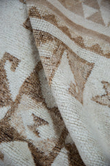 Close-up of the short, hand-knotted pile texture in ivory and coffee brown tones.