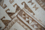 A Kurd rug's folded corner shows the textured wool pile and the geometric triangle border.