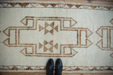Primitive geometric medallion design on a distressed Kurd runner in ivory and brown.
