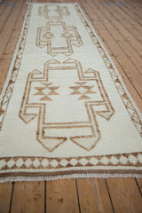 Distressed ivory pile with coffee brown primitive geometric patterns on a Vintage Kurd runner.
