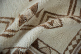 Close-up of the vintage distressed Kurd rug with textured ivory and brown primitive geometric pile.