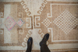 Textured, distressed pile on a Kurd rug showing checkered designs and a fuchsia blossom.