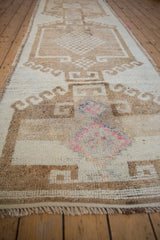 Worn texture of a distressed Kurd runner with fuchsia and blue details in a beige medallion.
