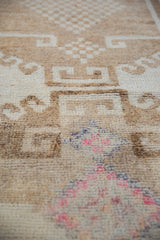 Distressed hand-knotted pile on a vintage Kurd rug with hook motifs and fuchsia accents.