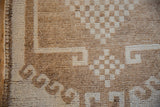 Distressed wool pile showing checkered and hook motifs beside the rug's intact side selvage.