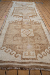 Angled shot of a distressed Kurd runner emphasizing its low, textured pile and geometric design.