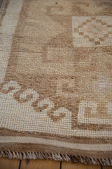 Low-pile texture of a distressed Kurd rug with visible knot heads in coffee and sand tones.