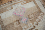 Distressed wool pile of a vintage Kurd rug showing knot heads and pops of fuchsia.