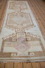 Angled perspective of a distressed Kurd runner with textured, neutral tones and fuchsia highlights.