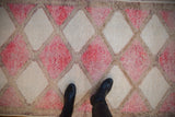 Geometric lattice of fuchsia, ivory, and time-softened tones on a vintage Kurd runner.
