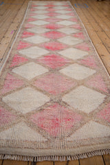 Textured close-up of distressed Kurd rug, showing fuchsia and ivory diamond panels with vinery.