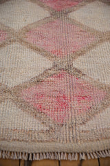 Textured pile of a distressed vintage Kurd runner, fuchsia and ivory geometric diamond patterns, with fringe.