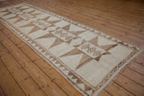 Angled view of a vintage Kurd runner's starburst medallions and mountain motif border.